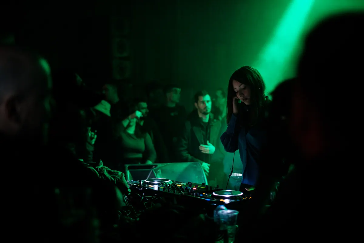 DJ za pultom u zelenom svjetlu, publika