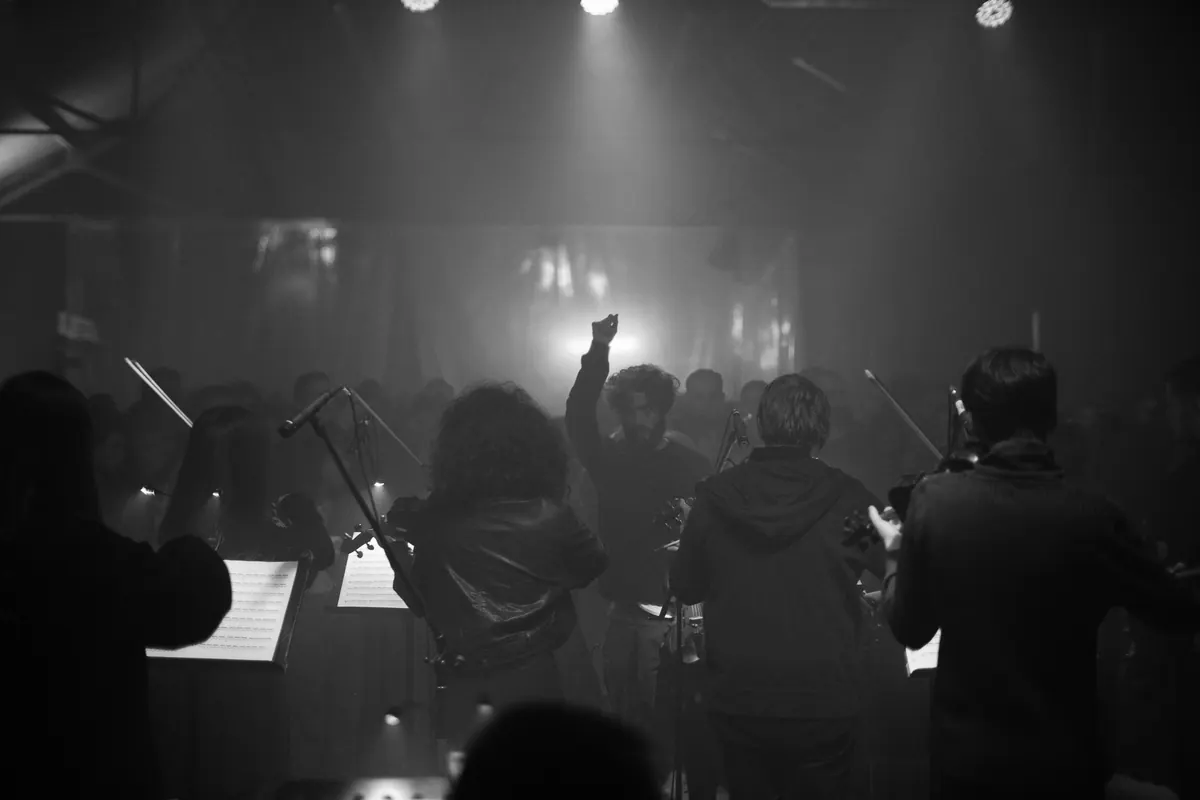 Crnogorski orkestar mladih s leđa okrenut publici, dirigent podignute pesnice, crno-bijelo